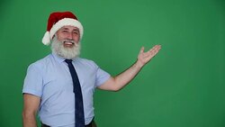 Senior businessman in hat of Santa Claus shows up space and shows the thumb on a green background Stock Footage
