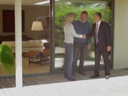 Wide, Track shot portrait of couple with estate agent in front of house Stock Footage