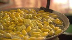 Silk cocoons boil in a kettle where a fork stirs them. Stock Footage