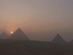 Wide Shot, static  - The sun resembles a pinpoint of fire behind a silhouette of the Great Pyramids / Egypt Stock Footage