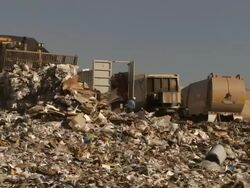 Medium Long Shot static - Trucks dump garbage as bulldozers spread it at a landfill / Bakersfield, California Stock Footage