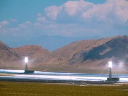 T/L solar thermal power plant with 300000 heliostat mirrors which reflect sun light into solar receiver boilers  set against mountain range and moving clouds overhead   / Ivanpah Dry Lake, California, USA Stock Footage