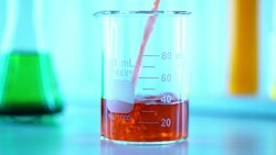 Pouring yellow liquid into Beaker Stock Footage