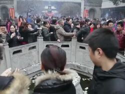 MS Pilgrims circle round wishing well to touch stone lion and drop money pray for good luck during Chinese Lunar New Year at Taoist temple / xi'an, shaanxi, china Stock Footage