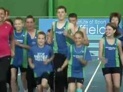 Jessica Ennis jogs for the camera on indoor track Stock Footage