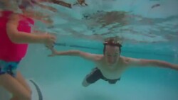 Young swimmer's father goes under the water and blows bubbles Stock Footage