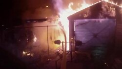 Slow motion firefighter POV spraying water onto burning garage Stock Footage
