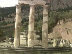 Medium Long Shot crane rack-focus - Ancient Greek writing remains on marble slabs at the Sanctuary of Athena where tourists roam. / Greece Stock Footage