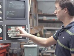 MS of young factory worker entering commands into keyboard control panel of Fadal milling machine / Redlands, California, USA Stock Footage