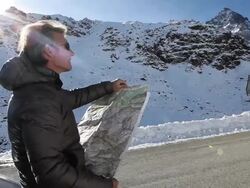 PAN of man reading map against car in snowy mtns Stock Footage