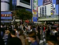 MS Crowd of pedestrians crossing street, city buildings and train passing in background, Shibuya, Tokyo, Japan Stock Footage