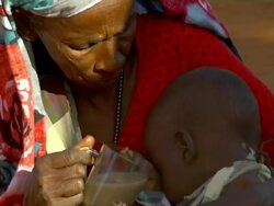 Old refugee woman trying to give milk to child Stock Footage
