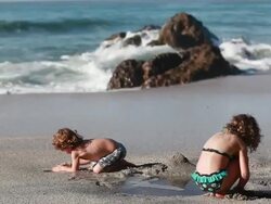 MS Boy and girl build sandcastle and play on beach with waves and ocean / Montezuma, Puntarenas, Costa Rica Stock Footage