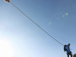 Pan of climber pulling rope tight to teammate, on cliff Stock Footage