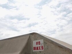 A young man rides his BMX bicycle and does a trick despite a sign that says 'No Bikes'. - Model Released - HD Stock Footage