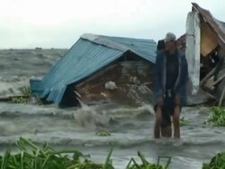 Men standing in flood waters as they swamp shanty houses; aftermath of typhoon Mirinae, Philippines Stock Footage