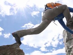 Mountaineer bridges gap between rocks, continues on Stock Footage