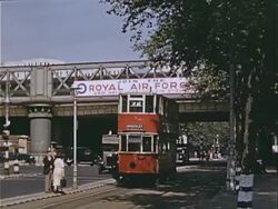 1939 Wide shot Pedestrians, double-decker bus and black taxis traveling on busy city street under Royal Air Force banner during war preparations / London, England  Stock Footage