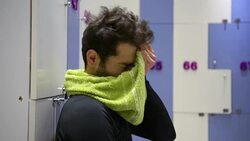 Young man resting and drinking water in the gym's locker room Stock Footage