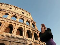 Tourist woman admiring the Coliseum (Colosseo) while passing by it Stock Footage