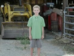 Slow motion push of boy with cleft lip smiling in front of tractor. Stock Footage