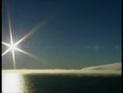 WA Starburst sun over calm sea, mist concealing land mass on horizon, Antarctica Stock Footage