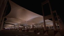 A van with rotating beacons passes under the canopy of a bus terminal in Saudi Arabia. Stock Footage