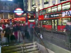 MS ZO T/L Shot of Piccadilly Circus Underground entrance night wide commuters enter and exit on steps traffic and shops restaurants in back side / London, Greater London, United Kingdom Stock Footage