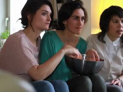 Girls on sofa watching Television and eating popcorn Stock Footage