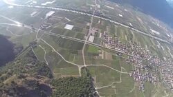 POV wingsuit flying over small town and releasing parachute Stock Footage