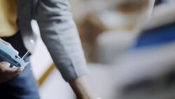 Young shop employee tags shirt in clothing store with tagging gun Stock Footage