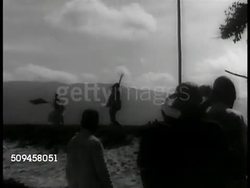 1937: REPUBLIC OF HAITI: Outdoor Voodoo (Vodou) sword dance (two men) on hill, mountains BG. CU Black hands holding drumsticks beating hand made drum. Instructional Video