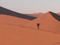 Man with tripod walking on sand dune, Sossusvlei, Namib-Naukluft, Namibia Stock Footage
