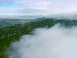 Aerial flight along clouds over the Bridger mountain range outside of Bozeman, MT Stock Footage