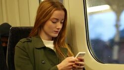 Attractive young woman on a train using her mobile phone. Stock Footage