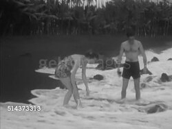 1953: HAWAII: BLACK SAND BEACH: Angled WS Male & female couple running up Punalu'u Beach Park black sand beach, VS Honeymooning couple being splashed by incoming wave, throwing seaweed back, rubbing sand on legs. Vacation destination, exotic, tropical. Instructional Video