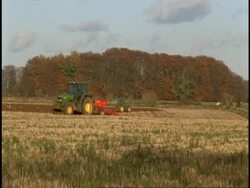Stroud, Gloucestershire - tractors plough stubble field in opposite directions, birds feed, trees on horizon Stock Footage