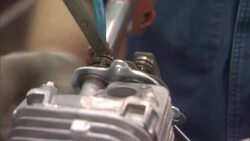 An assembly line worker uses a file, wrench and an automated screwdriver as he assembles carburetors. Stock Footage