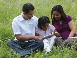 Asian family play together on ipad in mountain meadow Stock Footage