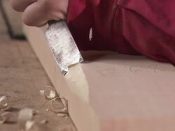 CU ZI Carpenter picking up chisel and chiseling piece of wood/ Slovenia Stock Footage