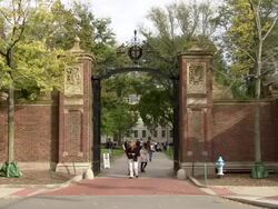 WS Entrance gate of  Harvard yard and  some women taking  pictures of  metal and brick fence AUDIO / Cambridge, Massachusettes, United States Stock Footage