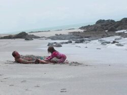 MS Man and boy lie on sand and are covered with sand while girl covers boy with sand / Montezuma, Puntarenas, Costa Rica Stock Footage