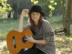 Young woman resting in park, holding guitar, smiling, posing outdoors. Stock Footage