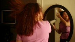 Woman Using Hairdryer in front of mirror Stock Footage