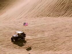 WS ZO PAN Offroad vehicles racing across hilly sand dunes in vast open desert / Glamis, California, USA Stock Footage