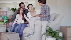 Family looking at photograph album on sofa surrounded by moving boxes Stock Footage