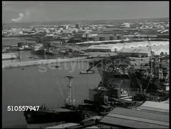1951: CASABLANCA, MOROCCO: PORT: HA VS Port, man-made harbor w/ docked ships, warehouse buildings, storage tanks. WS Tanker train moving into port. Phosphate pouring out of tube into cargo hold, pile of Phosphates in ship, export. Instructional Video