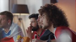 Sport fans sitting on couch watching tv and cheering Stock Footage