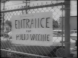 B/W 1962 PAN from "Entrance For Polio Vaccine" sign on fence to people waiting in line / Texas Stock Footage