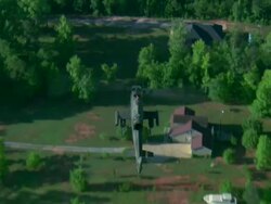 Air-to-air shot looking down on U.S. Army Cobra attack helicopter running at high speed over forested rural area Stock Footage